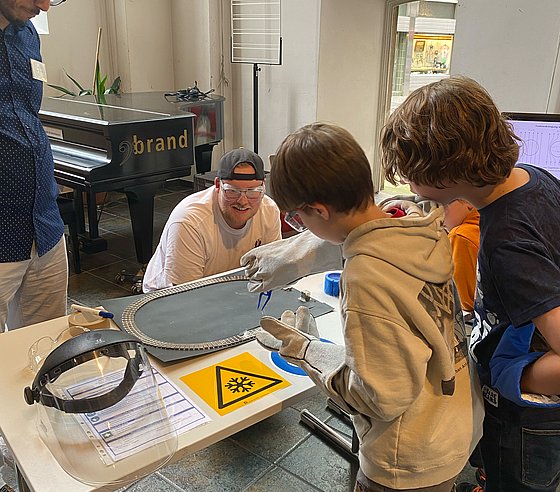 Zwei Kinder bringen in einem Experiment einen Magneten zum Schweben.