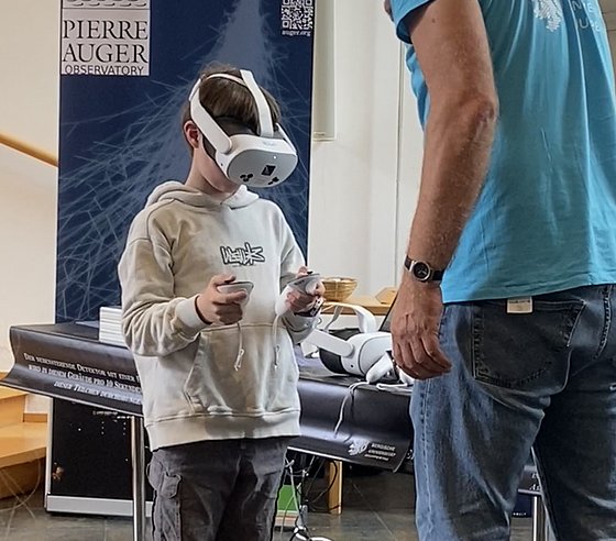 Ein Kind probiert eine VR-Brille unter Anleitung eines Physikers aus.